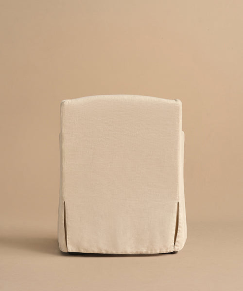 The Miramar Chair, shown from behind, features a cream hue, straight back, and tailored linen slipcover against a beige background.