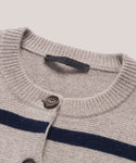 Close-up of the Cooper Cardigan, showing its structured silhouette, ribbed collar, dark buttons, two bold navy stripes across the taupe chest, and a black fabric label inside the collar.