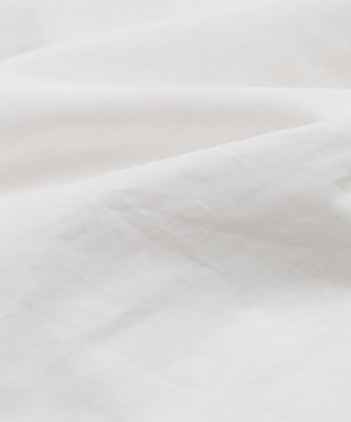 A close-up of Italian cotton poplin reveals soft folds and subtle shading, offering a smooth, lightly textured look—ideal for tailoring the elegant Newport Trouser.