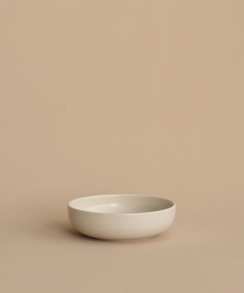 The Pacific Breakfast Bowl, with its simple round white design, rests on a beige surface against a matching background, adding elegance to your dinnerware collection.