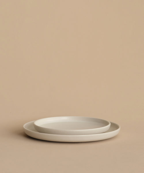 Two Pacific Salad Plates, simple and round, are stacked together on a neutral beige surface with a matching beige background.