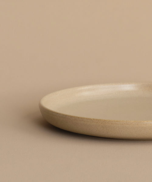 The Pacific Salad Plate, featuring a simple round design in beige, rests on a matching surface with a plain beige background.