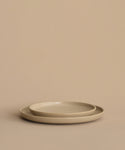 A pair of round beige stoneware dinner plates—a Pacific Salad Plate stacked inside a larger one—arranged on a plain beige background.