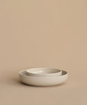 Two round, light beige Pacific Soup Bowls of different sizes are nested together on a matching beige surface with a plain beige background. Made of stoneware in Portugal.