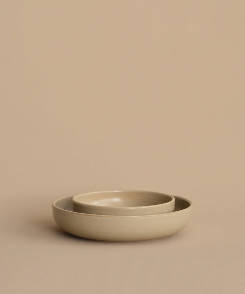 Two round beige Pacific Soup Bowls are nested together on a matching surface with a plain background, highlighting the elegant Pacific Soup Bowl stoneware dinnerware.