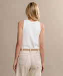 A woman with blonde hair, seen from behind, wears a Cotton Rib Tank in white and light beige high-waisted jeans against a plain neutral background.