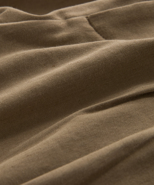 A close-up view of the Riley Trouser’s lightweight linen fabric shows its soft texture and gentle folds, creating smooth lines and shadows—ideal for a cool, summer-ready look.