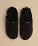 A pair of Suede Ashby Clogs in black with a fuzzy texture and a cozy shearling-lined footbed, displayed side by side on a beige background.
