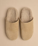 The Suede Ashby Clog, featuring a cozy shearling-lined footbed, is displayed in beige suede side by side on a light tan background.