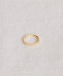 The James Band, a simple 14k solid gold ring, rests on a light textured fabric, reflecting the timeless elegance of heirloom-quality jewelry.