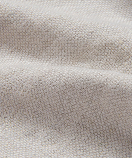 Close-up of Fabric Swatch Natural Linen featuring textured, light beige fabric with a bumpy woven surface and gentle folds that create soft shadows.