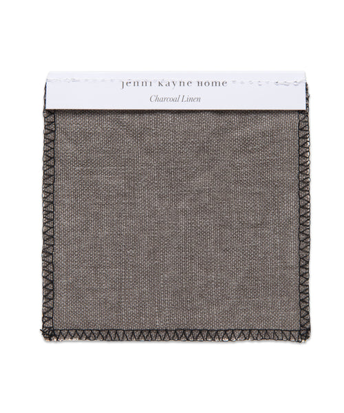 A square swatch of Charcoal Linen with black stitched edges, labeled “Fabric Swatch Charcoal Linen” on a white tag at the top—a signature touch for Jenni Kayne Furniture.